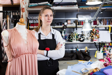 Portrait of woman designer who is standing on her workplace in time designing new collection in the workshop.