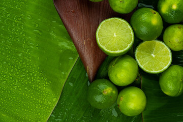 Pile of half and whole fresh lime juicy on green banana leaves with clearly water drop on surface