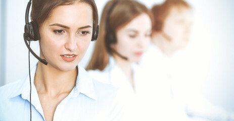 Call center operators. Focus on beautiful business woman using headset