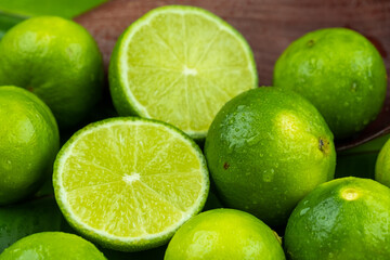 Close up pile of half and whole fresh lime juicy on green banana leaves with clearly water drop on surface