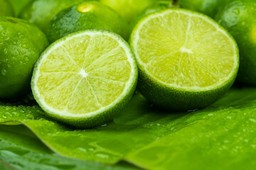 Close up pile of half and whole fresh lime juicy on green banana leaves with clearly water drop on surface