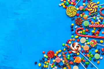 Collection of various candies and sweets on a blue background. Top view, flat lay, copy space.