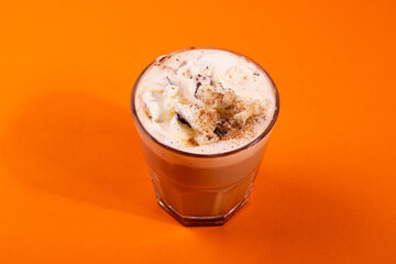 sweet yummy coffee in a glass cup on the orange background