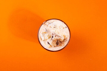 sweet yummy coffee in a glass cup on the orange background