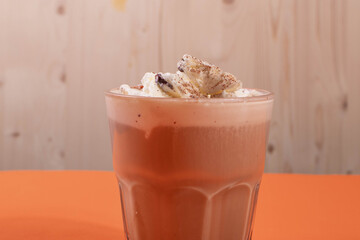 sweet yummy coffee in a glass cup on the orange background