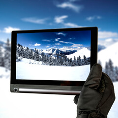 Hands with tablet and winter landscape of mountains 