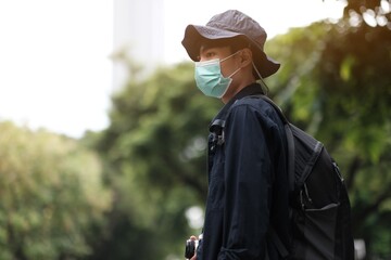 Asian travelers man in the forest with medical face mask to protection the Covid-19  new normal lifestyle