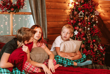 three children in pajamas on the bed having fun on Christmas morning