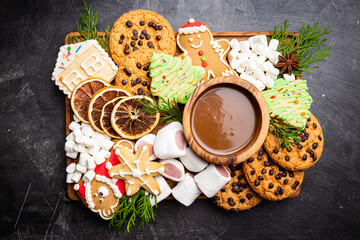 Christmas cookies and marshmallows with sweet dip sauce and festive decoration, top view