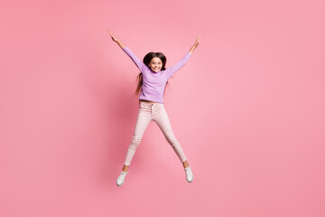Full length photo of carefree kid girl jump up raise hands isolated over pastel color background