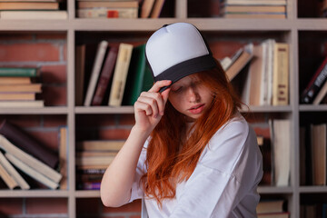 Portrait of a redhead woman in template blank t-shirt and cap with healthy freckled skin. Young...