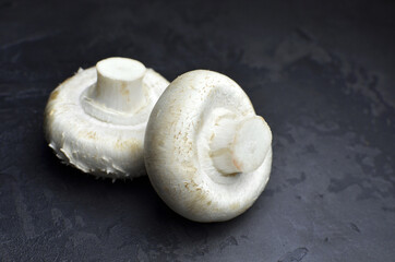 Raw organic champignon mushrooms on dark grunge background. Vegan lifestyle.
