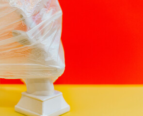 deer wrapped in a plastic bag on a colored red and yellow background, creative concept of protecting the planet from plastic