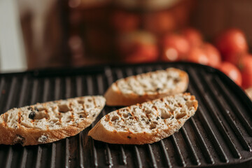 Bread slices on the black grill at home kitchen. Toasted ciabatta bread for bruschetta or sandwiches. Copy space. Cooking process. 