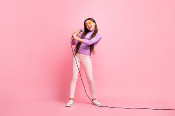 Full length photo of little kid girl sing son on mic wear violet jumper pants isolated over pastel...