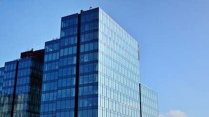 Obraz premium Blue curtain wall made of toned glass and steel constructions under blue sky. A fragment of a building.