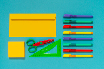 Flat lay of bright multicolored office supplies on a blue background. Top view