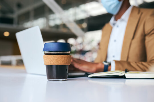 Businessman Wearing Mask With Reusable Coffee Cup Works On Laptop At Desk In Office During Pandemic