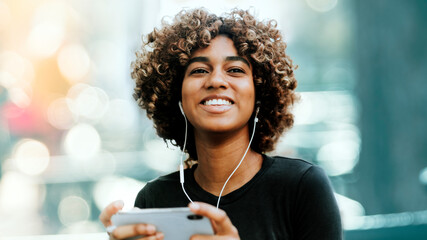 Girl listening to music from her phone - obrazy, fototapety, plakaty