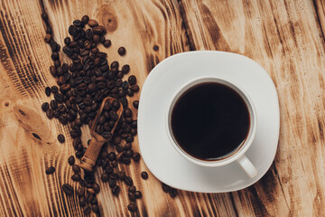 Cup of coffee  and roasted coffee beanson brown old wooden board background, top view. Rustic style.