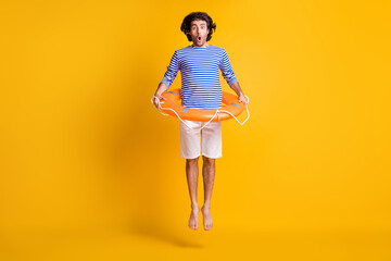 Fototapeta na wymiar Full body photo of shocked guy jump up wear orange rubber lifesaver shorts blue white shirt isolated on yellow color background