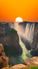 Supersized sun over Victoria Falls in Zambia with narrow canyon