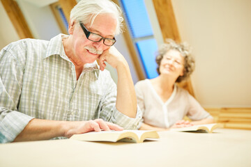 Obraz premium Senior man reads with joy in a book