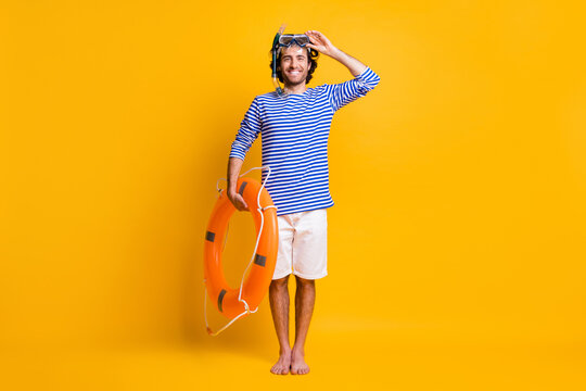 Full length photo of guy hold life buoy touch scuba goggles wear blue striped shirt shorts isolated on yellow color background