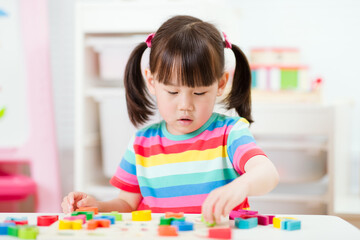 young  girl learning letter blocks for homeschooling
