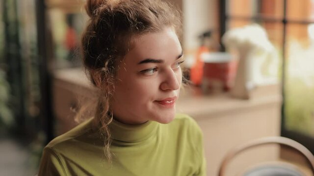 Young woman drinks a tea in the cafe with enjoyment