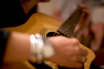 Selective focus with nice bokeh of a young woman playing the guitar