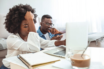 Young couple calculating their domestic bills at home. Young family discussing family finances. Serious worried african american couple reading documents consider mortgage loan insurance