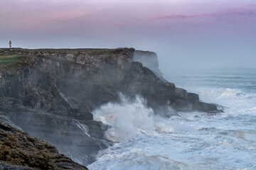 Obraz premium storm waves crash onto the Cape Ajo in Spain with the lighthouse on the cliffs above at sunrise