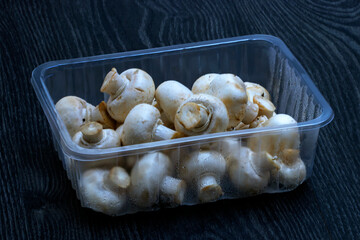 Champignons de Paris - Agaricus bisporus - dans un conditionnement plastique sur fond noir	
