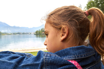 Little lonely girl in anxious emotion outdoors.