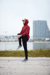 Fototapeta na wymiar Athletic sporty man training in hoodie sweatshirt in urban city park.
