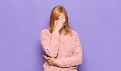 red head pretty woman looking stressed, ashamed or upset, with a headache, covering face with hand