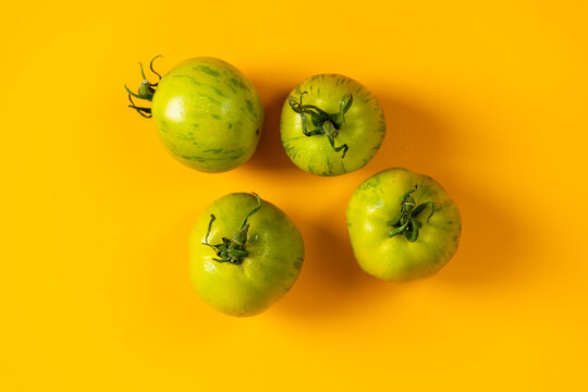 Different raw fresh green striped  tomatoes on yellow background. Concept of green house life style and products of subsistence farming, flat lay, copy space