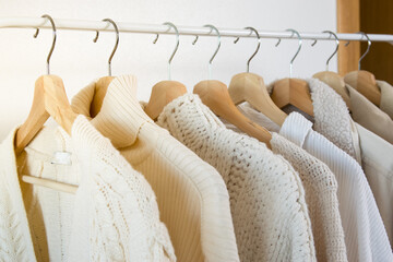 closeup of warm clothes like sweaters or coats hanging on hangers in a store or dressing room