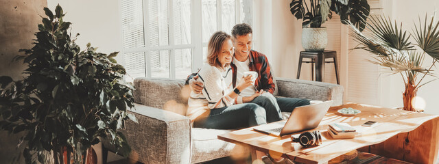 Family relationship. Happy couple at home on the couch watching movie using laptop