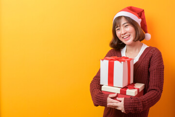Portrait of beautiful woman wearing red Santa Claus hat holding gift box over studio background, Christmas and New Year Concept