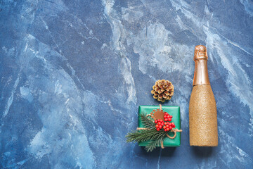 Christmas gift with bottle of champagne on color background