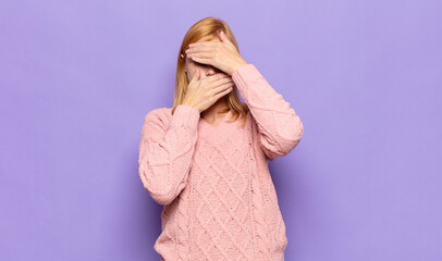 red head pretty woman covering face with both hands saying no to the camera! refusing pictures or...