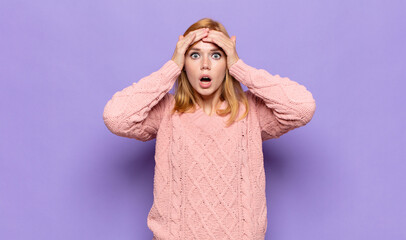 red head pretty woman feeling horrified and shocked, raising hands to head and panicking at a...