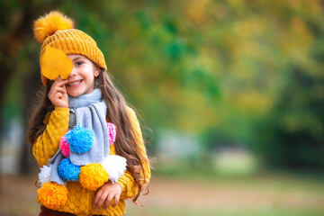 Autumn park and happy little girl playing with fallen tree leaves