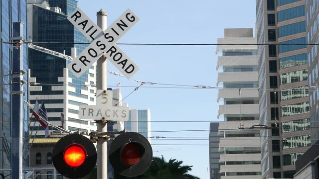 Level crossing warning signal in USA. Crossbuck notice and red traffic light on rail road intersection in California. Railway transportation safety symbol. Caution sign about hazard and train track.