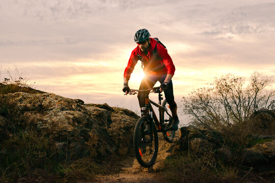 Cyclist in Red Riding Bike on the Autumn Rocky Trail at Sunset. Extreme Sport and Enduro Biking Concept.