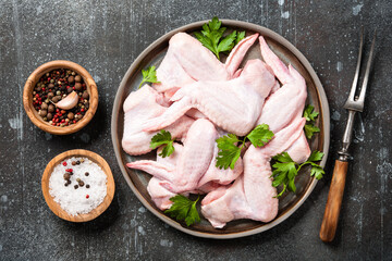 Fresh raw chicken wings on ceramic plate and spices for cooking