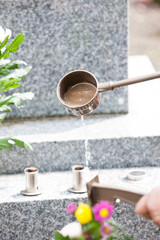 お墓に水をかける男性