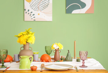 Beautiful table setting with pumpkins and autumn leaves in dining room